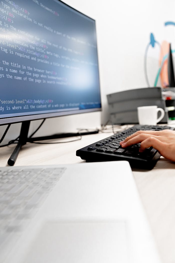 Mastering the First Impression: Your intriguing post title goes here Close-up of hands typing code on a computer monitor in an office setting.